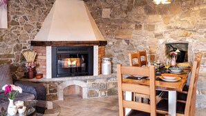A stone fireplace with a modern design, a dining table set with plates and glasses, and a cozy seating area with a sofa and a side table.