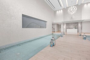 Un vaste espace intérieur abritant une piscine, avec un comptoir d’accueil et un éclairage moderne.