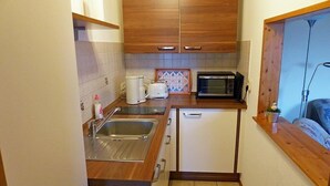 A compact kitchen with wooden cabinets, a microwave, a coffee maker, and a sink.