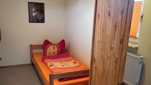 A small bedroom with a single bed, a wooden wardrobe, and a radiator.