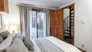 Une chambre à coucher avec un lit, une fenêtre avec des rideaux, une porte et un escalier.