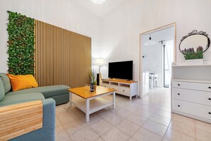 A modern living room with a sofa, a coffee table, a TV, and a decorative wall panel. - Eva Apartment Bari (Bari)