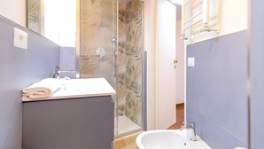 Un bagno con box doccia in vetro, lavandino e specchio.