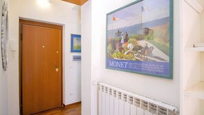Un corridoio con una porta in legno, un quadro di Monet e un termosifone bianco.