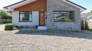 A small, single-story house with a brick facade, a wooden front door, and a small porch. - Fircroft (Perth)