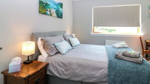 A neatly arranged bedroom with a bed, bedside lamp, and a window with a view. - Fircroft (Perth)