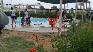 Un espacio al aire libre cubierto con una piscina, rodeado de follaje y una persona manejando una cámara.