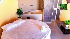 Un dormitorio con una cama grande, una mesita de noche con una planta, un baño con bañera y un armario.