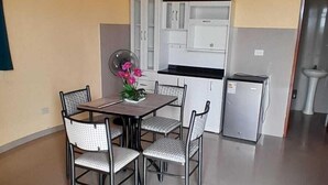 Un comedor con mesa y sillas, una cocina con armarios y electrodomésticos, y un piso de baldosas.