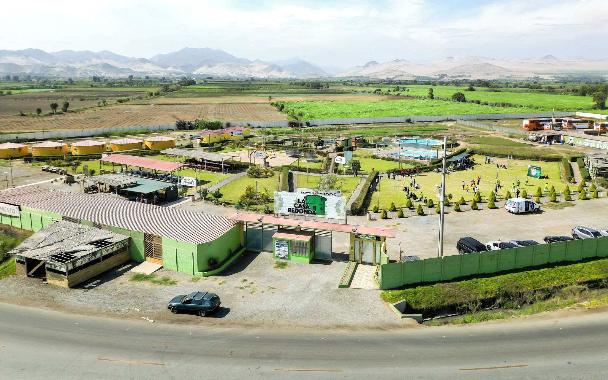 Un complejo amplio y al aire libre con varias construcciones, piscina y zona de estacionamiento.