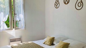 A bedroom with a bed, white bedding, a window with sheer curtains, and wall art. - At the foot of the dunes and the beach! Ideal for a quiet place (Barbâtre)