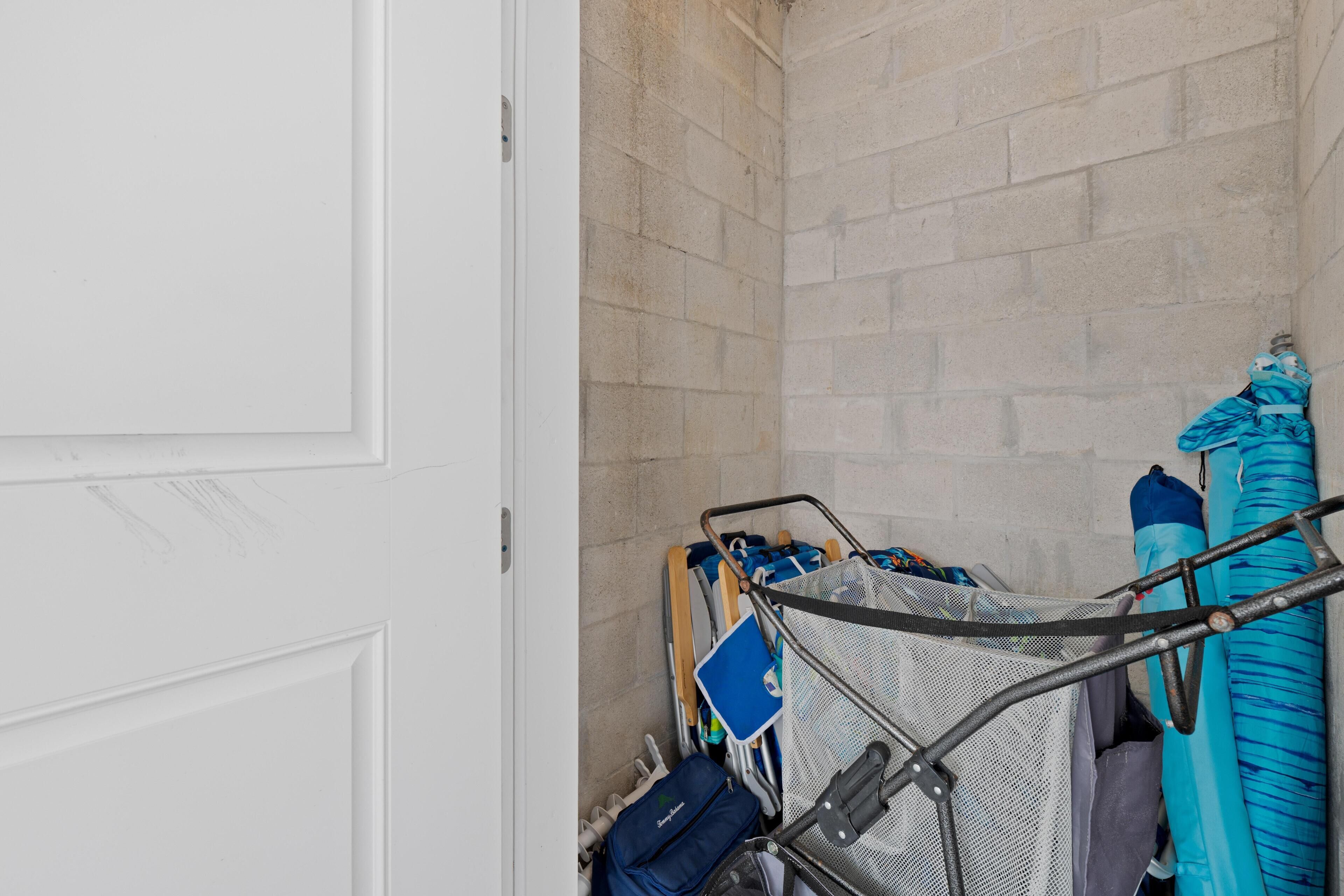 A narrow hallway with a white door on the left and a luggage rack with various bags and suitcases on the right.