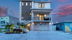 Une maison moderne à deux étages, dotée d’un garage fermé, d’un balcon et d’une enseigne indiquant « Mod Cottage ».