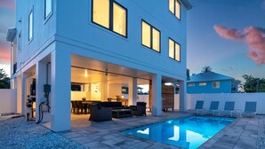 Une maison moderne dotée d’une piscine, d’un espace salon extérieur et d’un patio couvert.