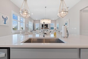 A modern kitchen with a central island, stainless steel appliances, and pendant lighting. - Mod Cottage (Fort Myers Beach)