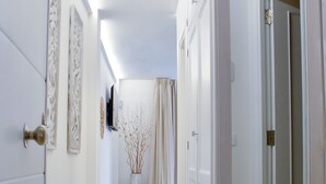 A hallway with white walls, a tiled floor, and doors with decorative moldings.