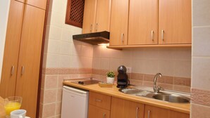 A kitchen with wooden cabinets, a stainless steel sink, a coffee maker, and a dishwasher.