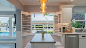 A modern kitchen with a dining area, large windows, and a view of a pool. - High Tide Hideaway (Fort Myers Beach)