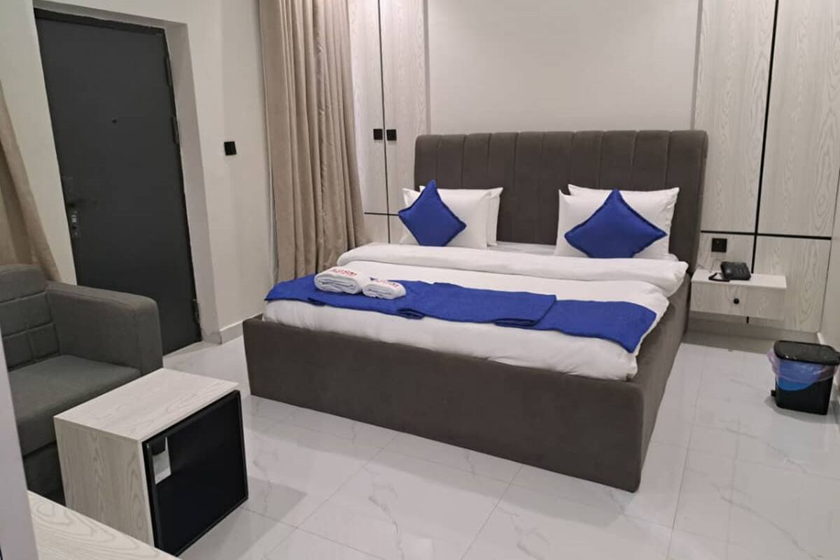Een moderne slaapkamer met een groot bed, een kleine zithoek en een nachtkastje.