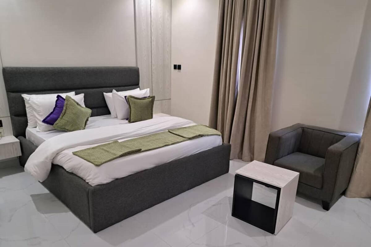 Een moderne hotelkamer met een groot bed, een nachtkastje, een stoel en een klein bijzettafeltje.