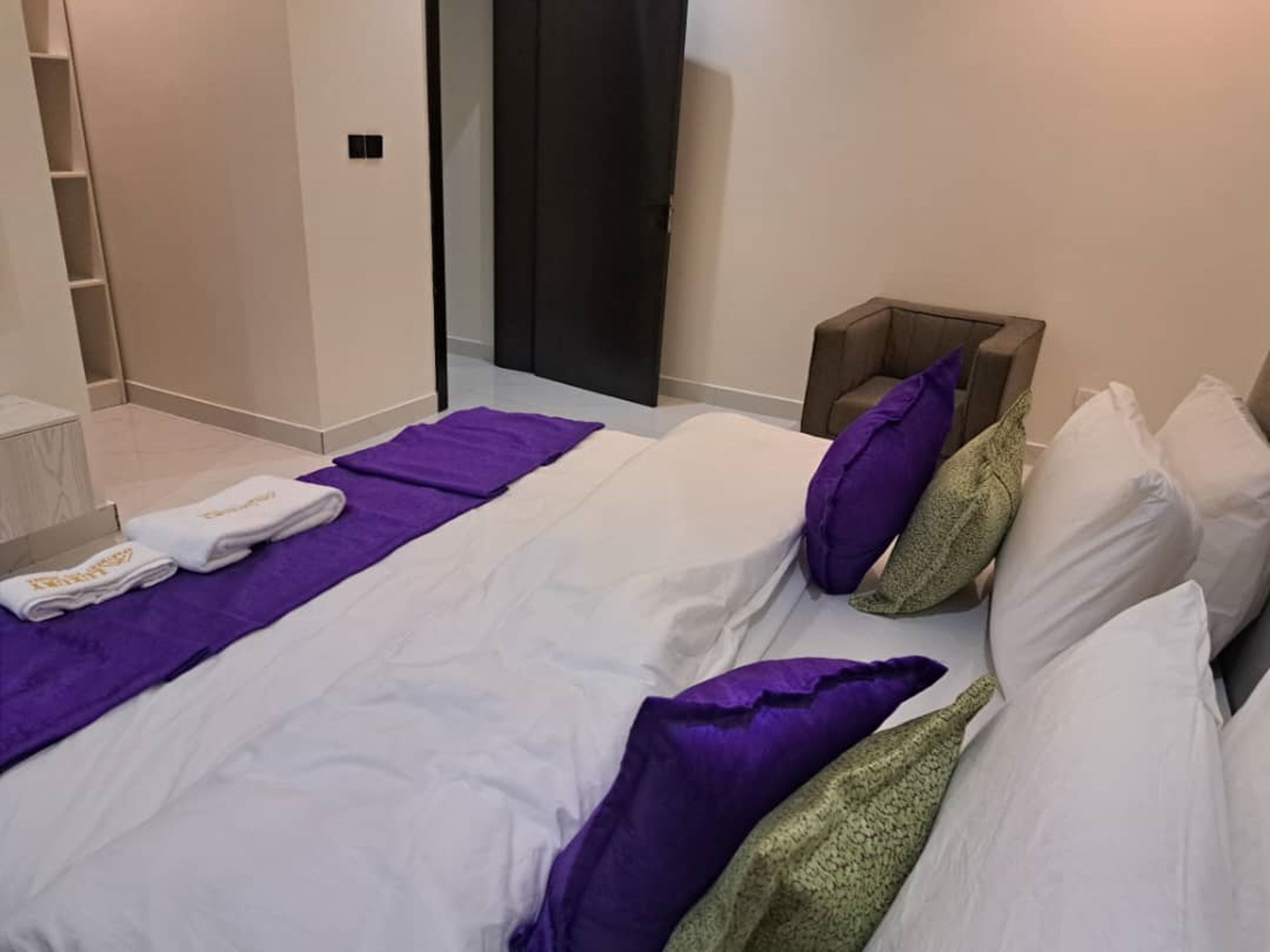 A hotel room with a bed, a bathroom, and a wardrobe.