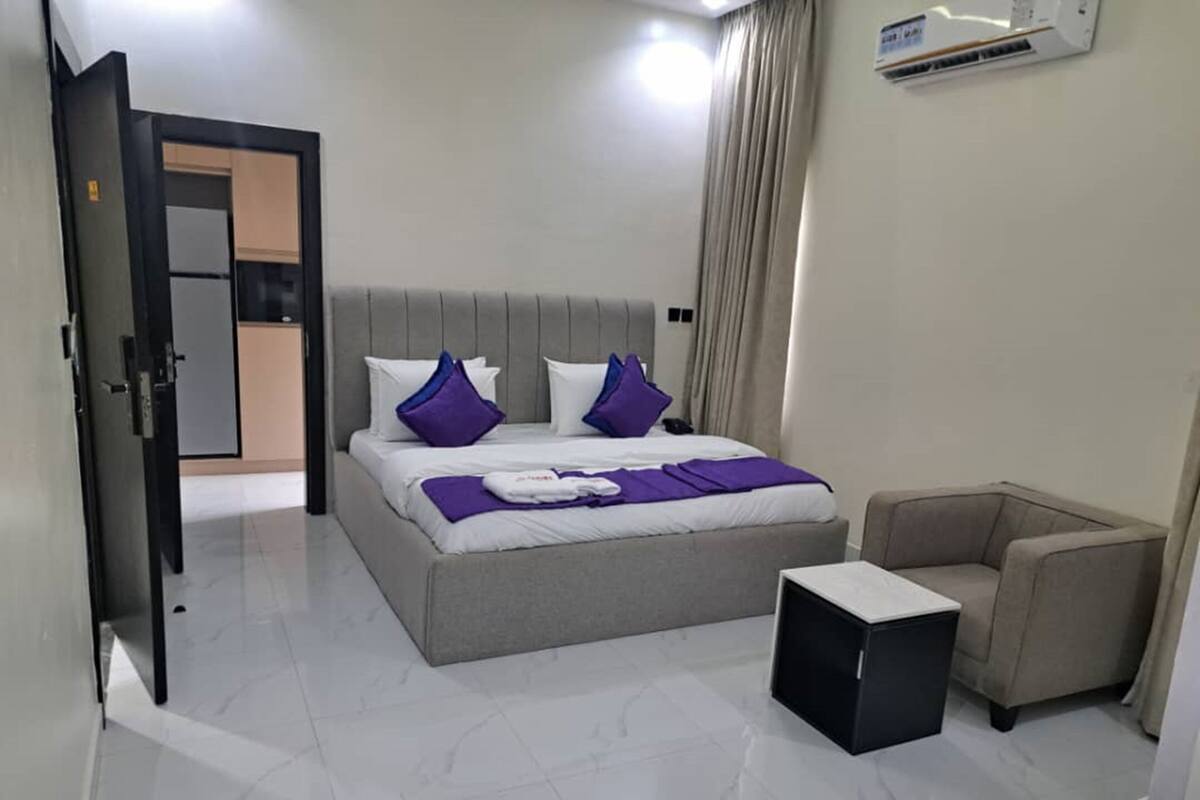Een moderne hotelkamer met een groot bed, een fauteuil en een klein bijzettafeltje.