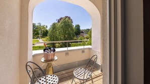 Ein Balkon mit Tisch und Stühlen, Blick auf Grünflächen und ein Gebäude in der Ferne.