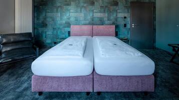 Uma cama de casal com cabeceira rosa num quarto com parede em padrão de pedra e carpete escuro.