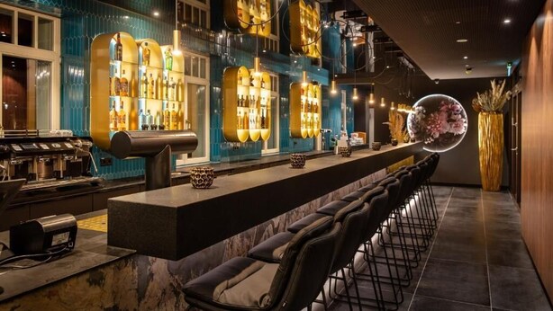 Eine Bar mit einer langen Theke, zahlreichen Flaschenregalen und Barhocker.