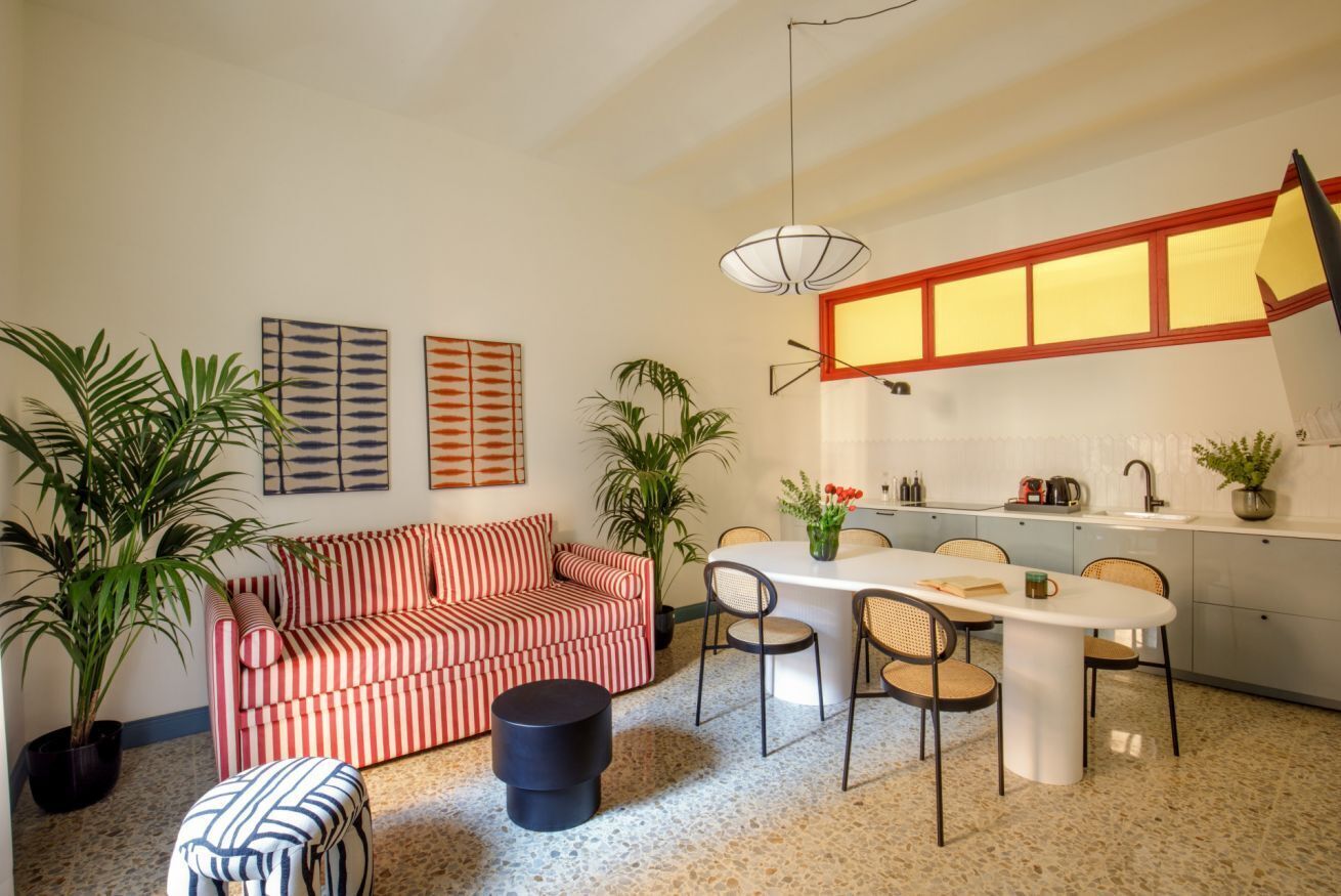 Un salon moderne avec un canapé à rayures, une table à manger avec des chaises et un coin cuisine avec une fenêtre au-dessus de l’évier.