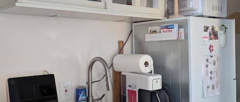 Cocina compacta con microondas, cafetera y pileta.