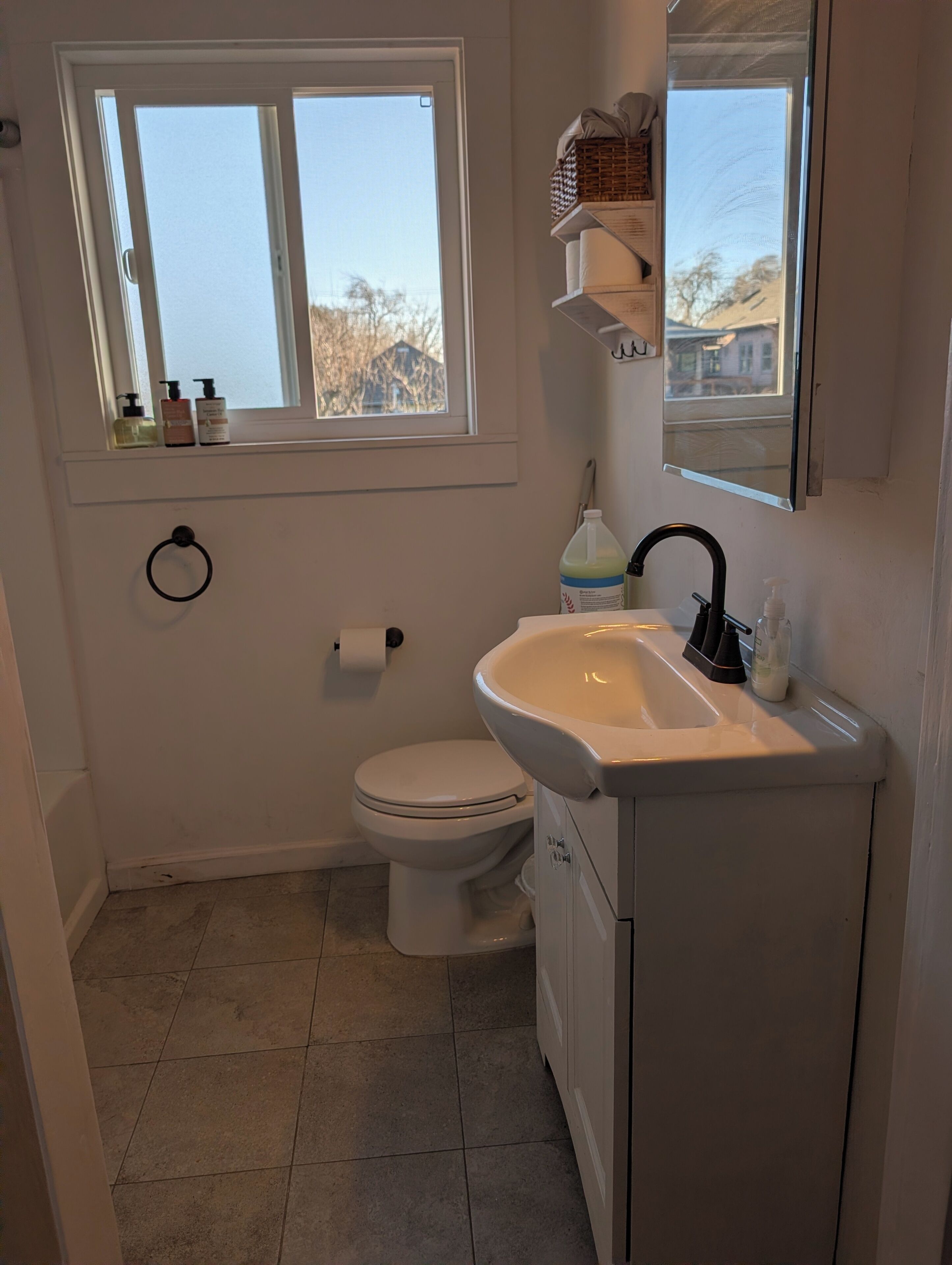 A bathroom with a toilet, sink, and window.