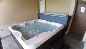 A hot tub in a room with tiled flooring and a door.
