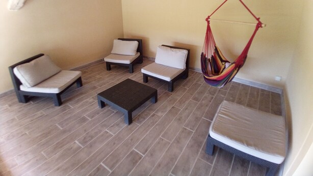 A sunlit patio with two lounge chairs, a small table, and a colorful hanging chair.