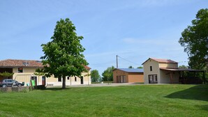 A residential area with a grassy lawn, a playground, and buildings with a red-tiled roof.