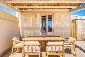 A wooden table with four chairs, a glass vase, and a door leading to an interior space.