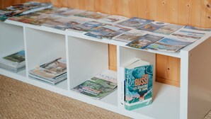 Uno scaffale bianco con riviste e libri, tra cui si nota un libro intitolato 'Les Assassins de la Baie' di Michel Bussi.