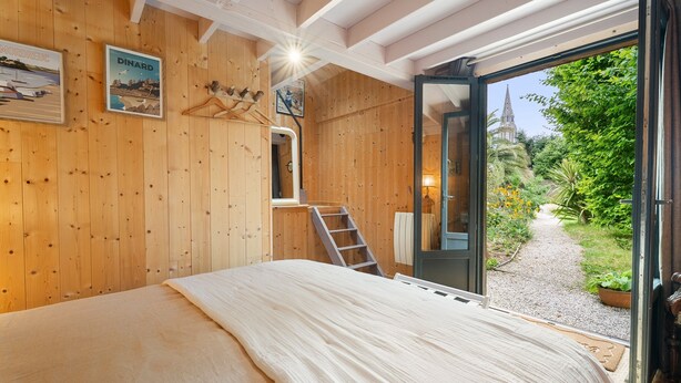 Una stanza in legno con un letto, una scala e una porta che dà su un giardino.