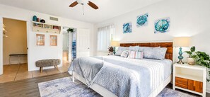 A bedroom with a bed, bedside tables, artwork, and a bench.