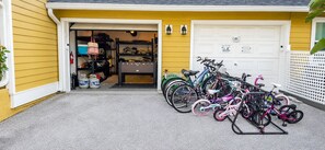 Eine Garage mit draußen abgestellten Fahrrädern, einem Feuerlöscher und Regalen mit diversen Gegenständen.