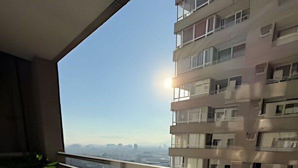 A balcony with a view of a cityscape, a table, and a chair. - Collection R 5 MONEDA 2 Presidencial  (Santiago)