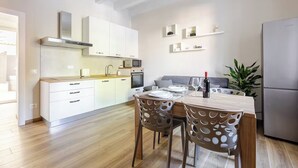 A modern kitchen with white cabinets, a wooden dining table, and a built-in oven. - Suite 53 Campofiore - with outdoor patio (Verona)
