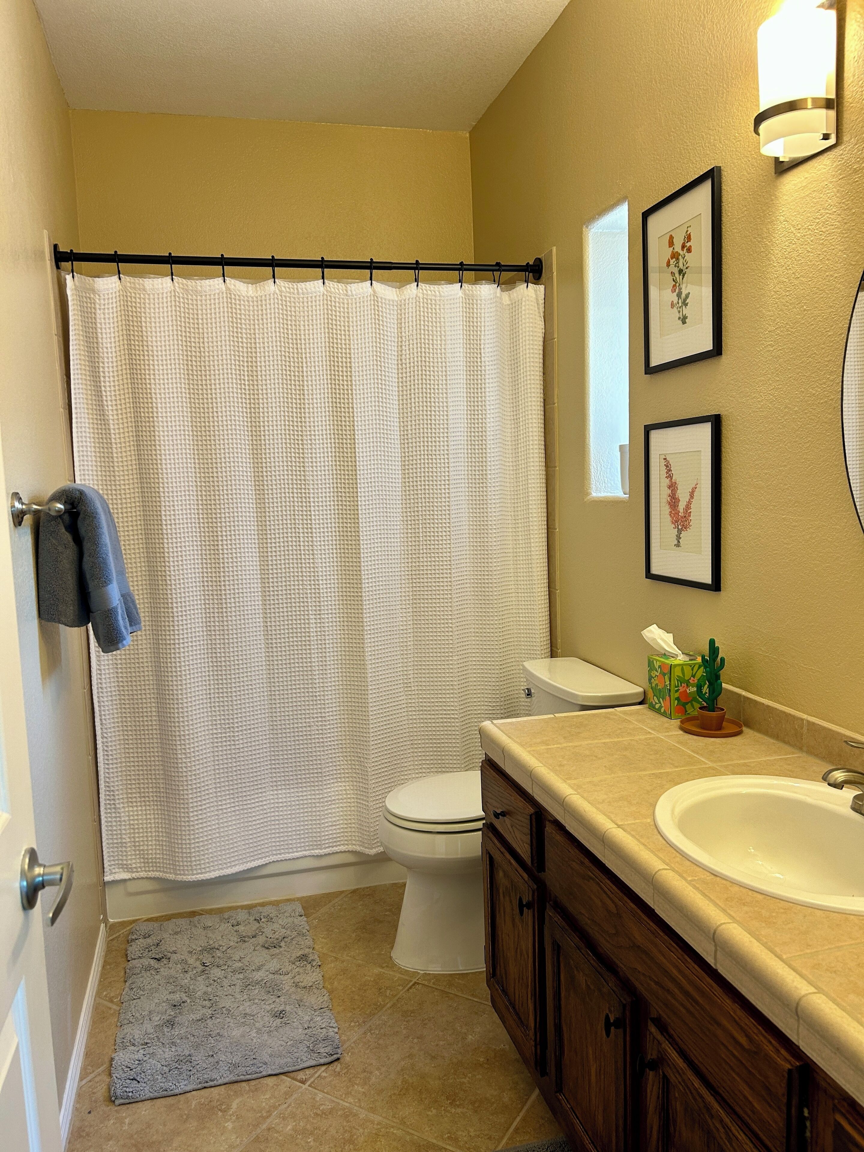Ein Badezimmer mit Duschvorhang, Toilette, Waschbecken und gerahmten Bildern an der Wand.