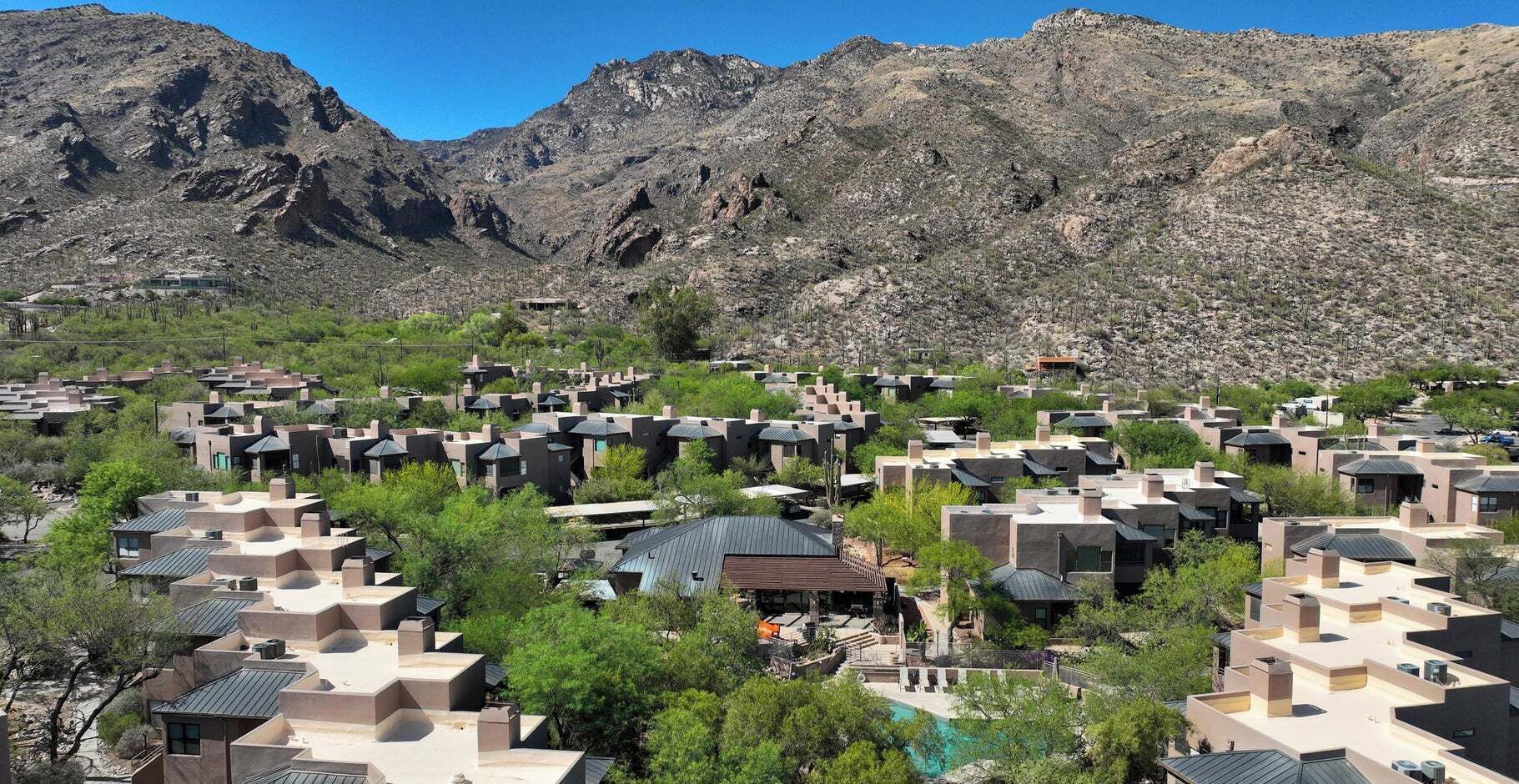Ein Resort mit mehreren Gebäuden, einem Schwimmbad und einem Bergpanorama im Hintergrund.