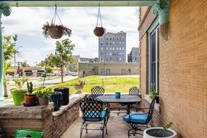 Eine Terrasse mit Tisch und Stühlen, Blumentöpfen und hängenden Pflanzgefäßen.