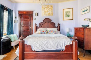 Una camera da letto con un letto a baldacchino in legno, una cassettiera, una scrivania e un lampadario.