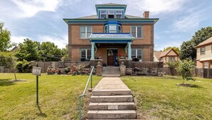 A two-story house with a front porch, a staircase leading to the entrance, and a well-maintained lawn.