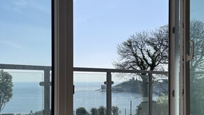 Vista desde una ventana que da a un cuerpo de agua, un puente y un árbol.