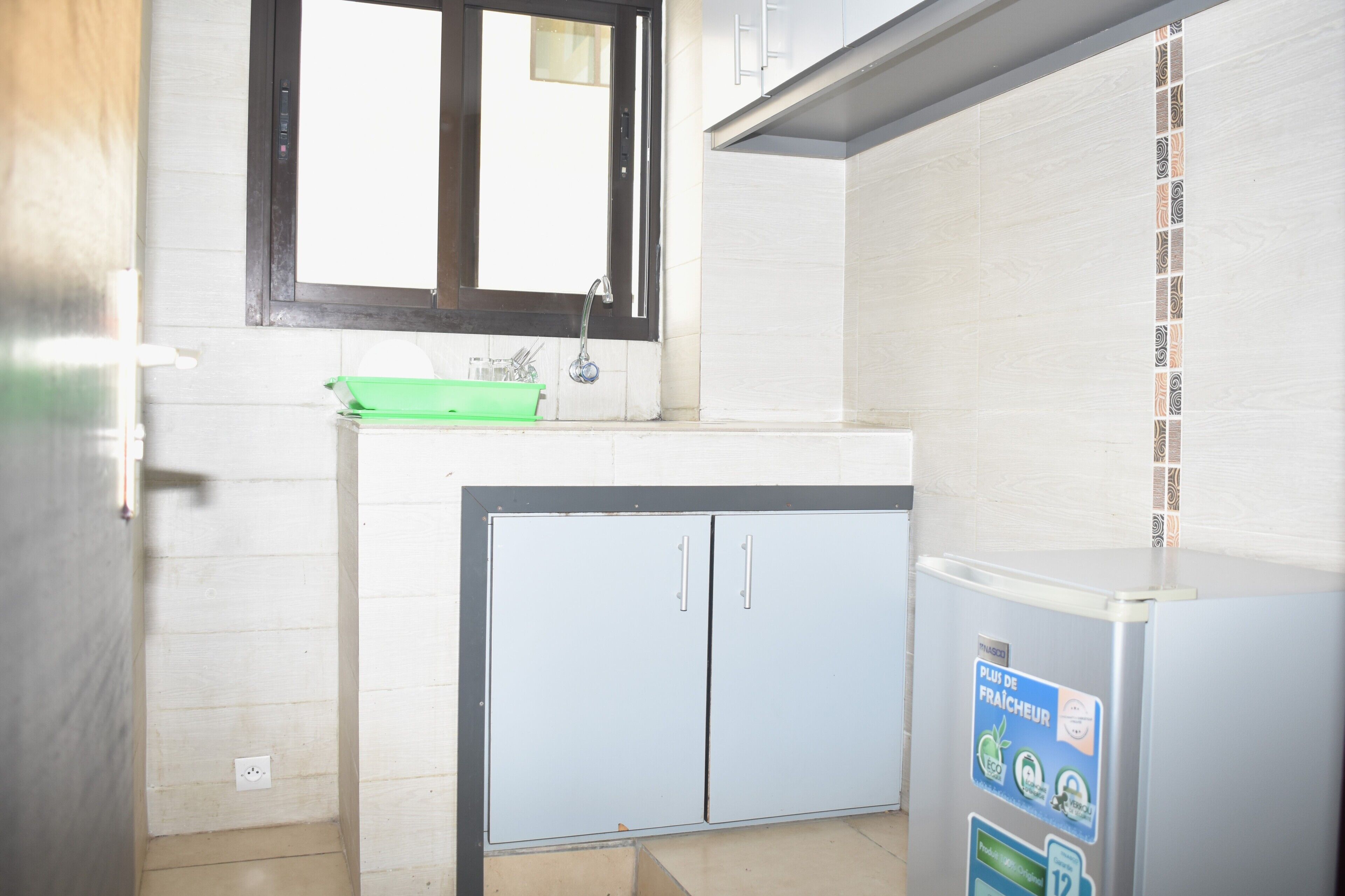 Una cocina con fregadero, armarios y refrigerador.