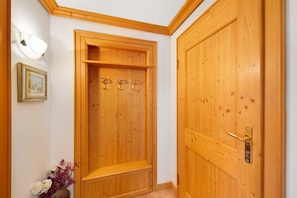 Una puerta de madera con manija y cerradura, un banco de madera y una lámpara fijada a la pared.